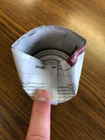 Starting at the outer seam, fold the top edges of the newspaper cylinder inward, over the top of the can. (Matt Fowler)