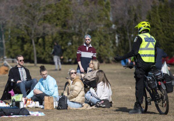 Police talk with people as they gather in a park in Montreal on April 4, 2021. (The Canadian Press/Graham Hughes)