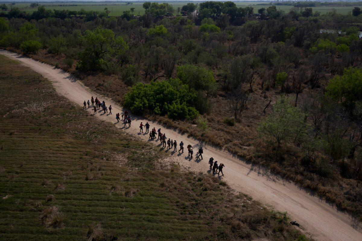 Families from Central America walk towards the border wall after crossing the Rio Grande river into the United States from Mexico on rafts in Penitas, Texas on March 26, 2021. Picture taken with a drone. (Adrees Latif/Reuters)