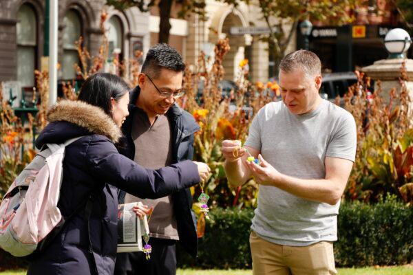 Bendigo Councillor Vaughan Williams (R) speaks with Falun Dafa practitioners (L) giving out lotus flowers in Bendigo, Victoria, on April 10, 2021. (The Epoch Times)