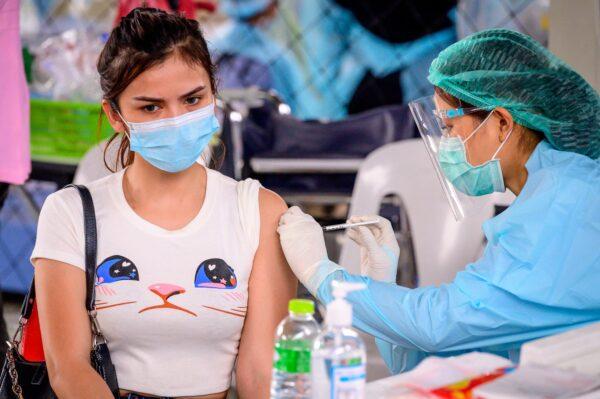 A health worker administers the CoronaVac vaccine, developed by China's Sinovac firm, to a woman from an at-risk group at Saeng Thip sports ground in Bangkok, on April 7, 2021. (Mladen Antonov/AFP via Getty Images)
