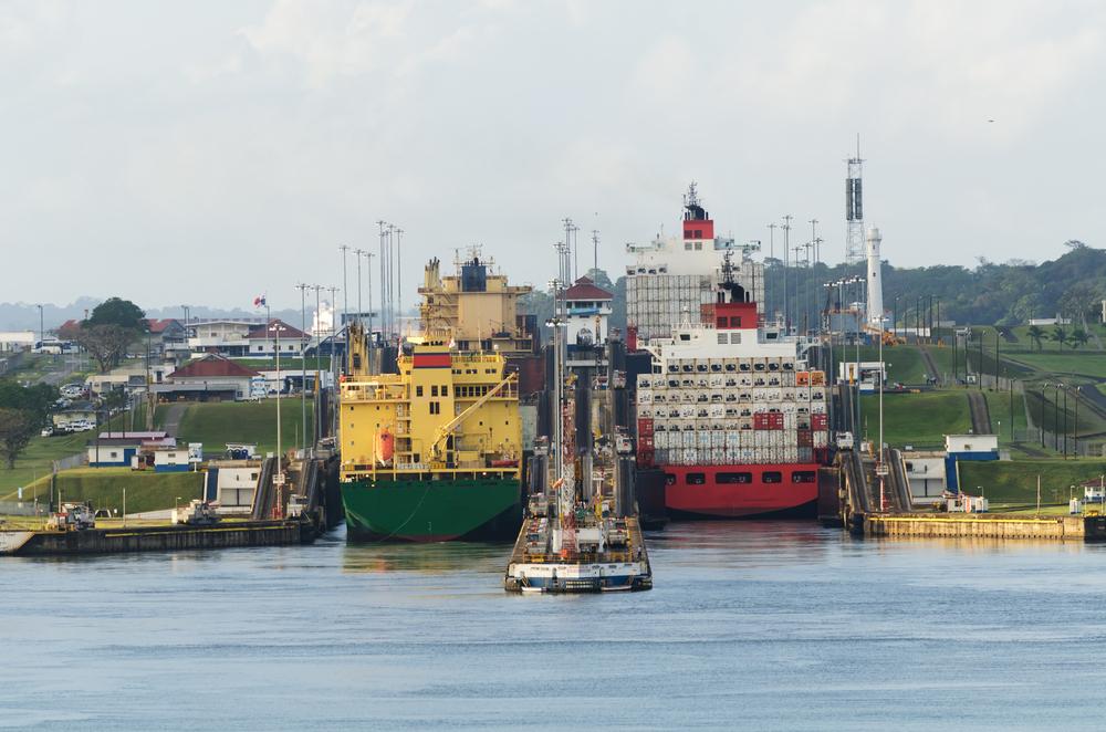 Two cargo ships enter the Gatun Locks from the Gatun Lake in the Panama Canal. (Blackmac/Shutterstock)