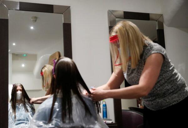 Kelly Boad, owner of Hair & Beauty Gallery, gives Sue Butcher a haircut as non-essential businesses reopen as COVID-19 lockdown restrictions begin to ease in Warwick, Britain, on April 12, 2021. (Andrew Boyers/Reuters)