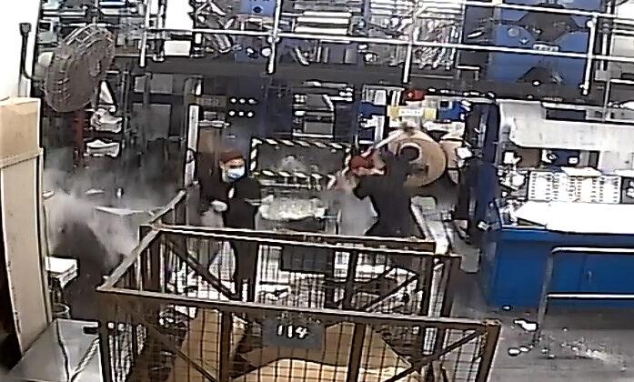 A CCTV screenshot showing intruders dressed in black, one wielding a sledgehammer, damaging printing press equipment at the print shop of the Hong Kong edition of The Epoch Times on April 12, 2021. (The Epoch Times)