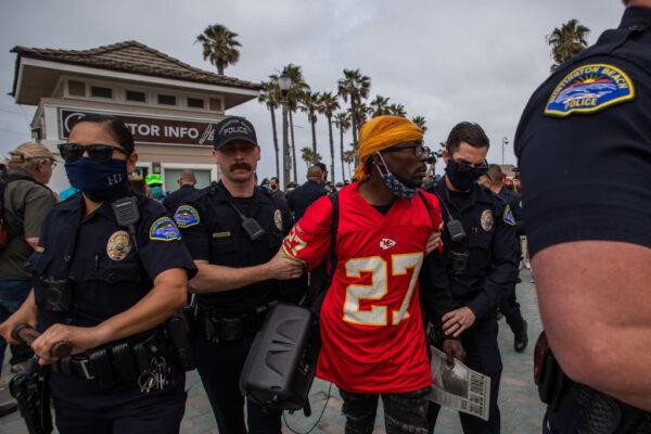 Police officers arrest a man for noise violation during a protest against white supremacy in Huntington Beach, Calif., on April 11, 2021. (Apu Gomes/Getty Images)