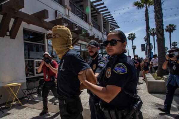 Police officers detain an alleged Proud Boy member during a protest against white supremacy in Huntington Beach, Calif., on April 11, 2021. (Apu Gomes/Getty Images)