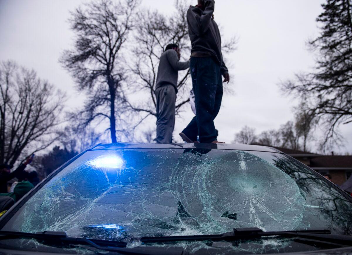 People stand on a police cruiser damaged during rioting in Brooklyn Center, Minn., on April 11, 2021. (Stephen Maturen/Getty Images)