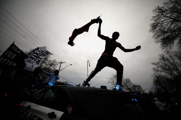 A demonstrator jumps off a police cruiser during civil unrest after an officer-involved shooting in Brooklyn Center, Minn., on April 11, 2021. (Nick Pfosi/Reuters)