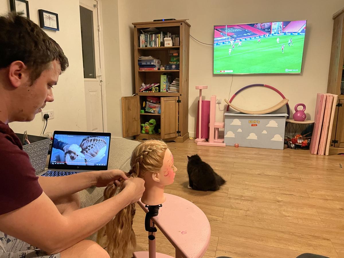 Callum practicing on a doll's head while watching football. (Kennedy News and Media)