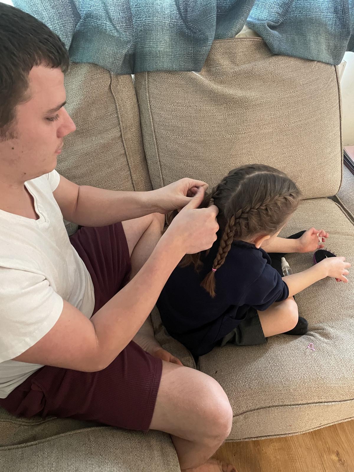 Callum plating his daughter's hair. (Kennedy News and Media)