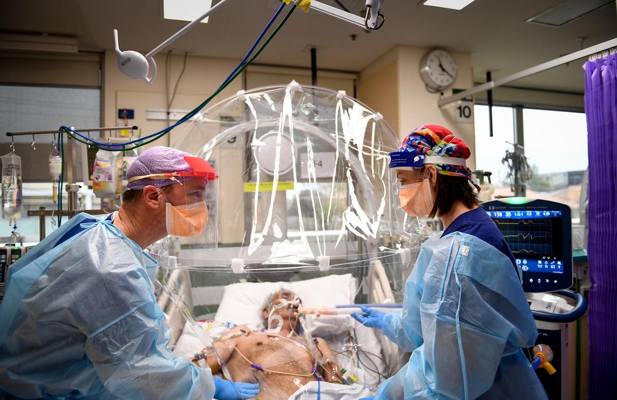 ICU nurse Michelle Spiteri and anesthetist and intensive care physician Dr. Forbes McGain attend to a COVID-19 patient under the COVID Hood developed by McGain and Melbourne University on July 17, 2020. (Penny Stephens/Western Health)