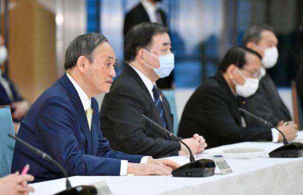 Japanese Prime Minister Yoshihide Suga, left, attends a cabinet meeting at his official residence in Tokyo, April 12, 2021. (Yoshitaka Sugawara/Kyodo News via AP)