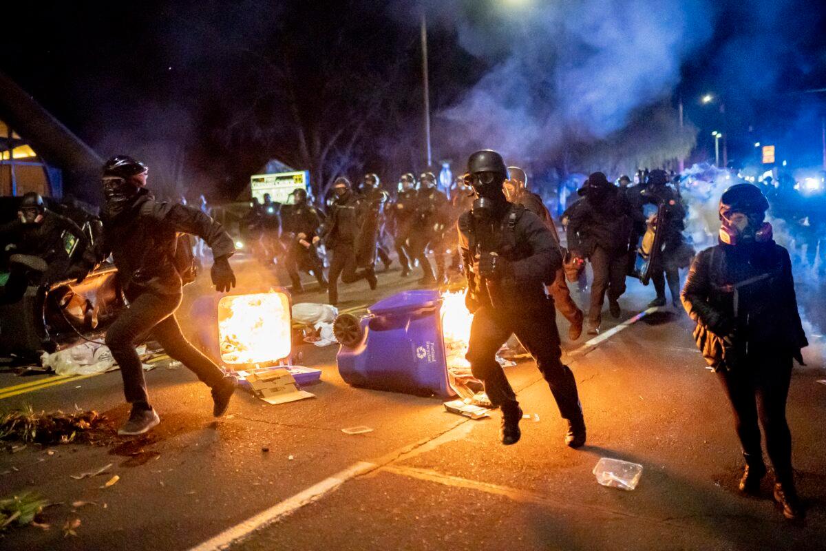 Portland police officers chase demonstrators after a riot was declared during civil unrest over the shooting in Minnesota of Daunte Wright, in Portland, Ore., on April 12, 2021. (Nathan Howard/Getty Images)
