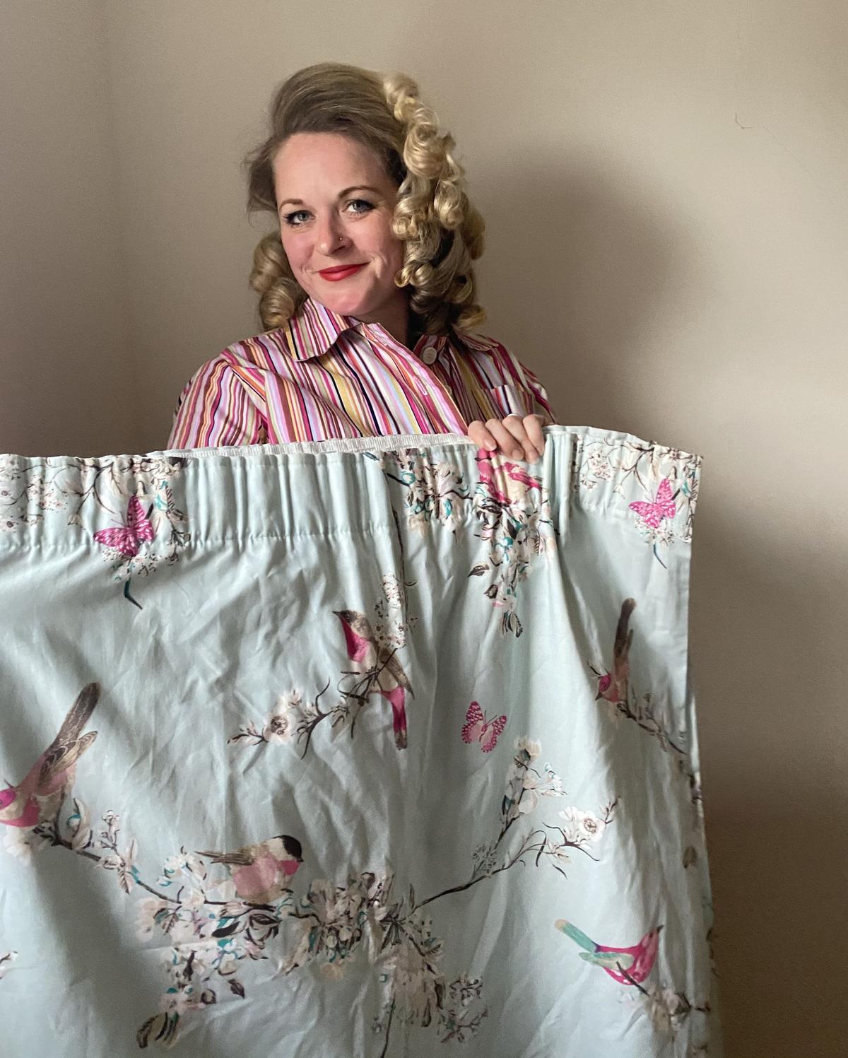 Rosie holding up some charity shop curtains she plans to make into an outfit. (Kennedy News and Media)
