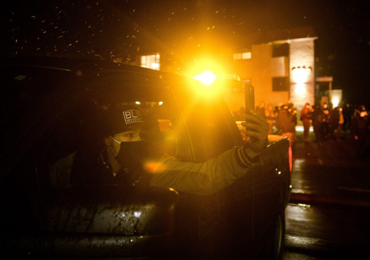 A man films on his mobile phone as people riot outside the Brooklyn Center police headquarters in Brooklyn Center, Minn., on April 13, 2021. (Stephen Maturen/Getty Images)
