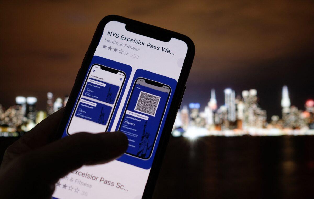 This illustration photo taken in Los Angeles on April 6, 2021, shows a person looking at the app for the New York State Excelsior Pass, which provides digital proof of a COVID-19 vaccination, in front of a screen showing the New York skyline. (Chris Delmas/AFP via Getty Images)