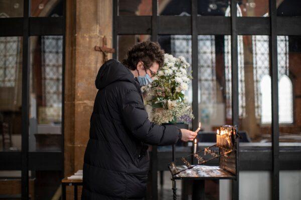 A woman lights a candle of remembrance during a small service at St. Catherine's Church in London on March 23, 2021. (Dan Kitwood/Getty Images)