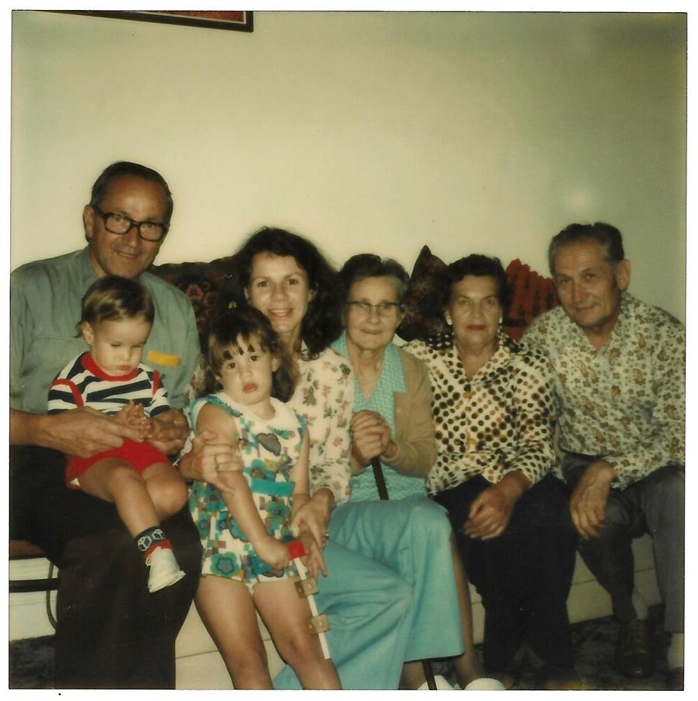 The author with her grandfather Dzeda, brother Matthew (on Dzeda's lap), mother, grandmother Buba, and two Latvian family friends. (Courtesy of Emma Buls)