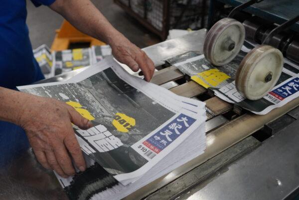 Newspapers of the Hong Kong edition of The Epoch Times come out of the printing press as the outlet resumes print after an attack on the printing facility on April 12, 2021. (The Epoch Times)