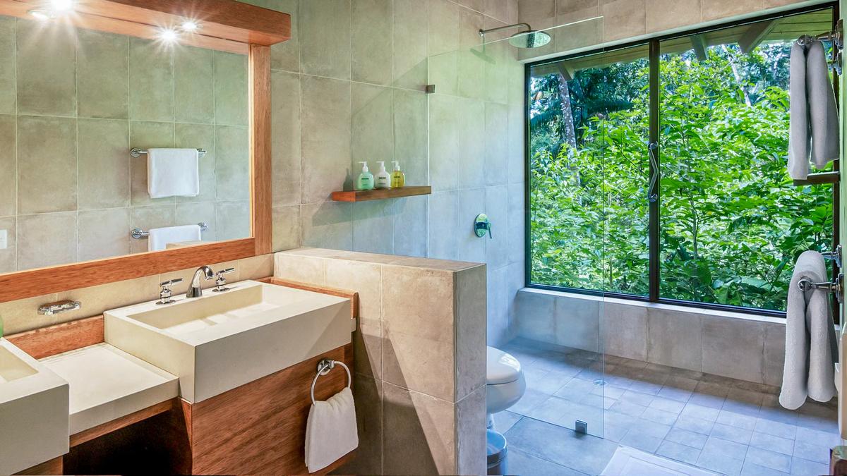A master bathroom in a suite featuring windows looking directly looking out into the rainforest at the Sacha Lodge in Ecuador. (Courtesy of Sacha Lodge)