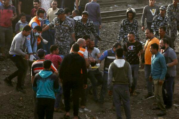 Medics carry an injured man at the site where a passenger train derailed injuring at least 98 people, in Banha, Qalyubia province, Egypt, on April 18, 2021. (Fadel Dawood/AP Photo)