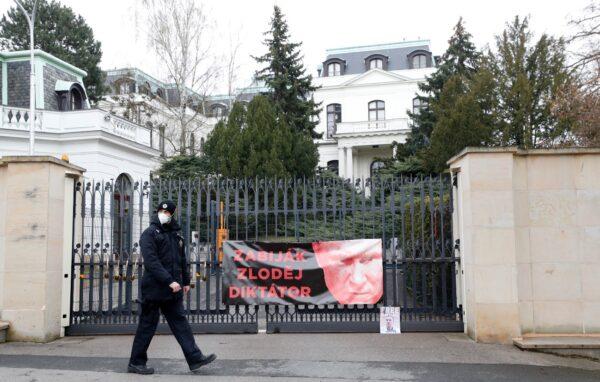 A policeman walks by a poster attached by protesters to a gate of the Russian embassy in Prague, Czech Republic, on April 16, 2021. (Petr David Josek/AP Photo)