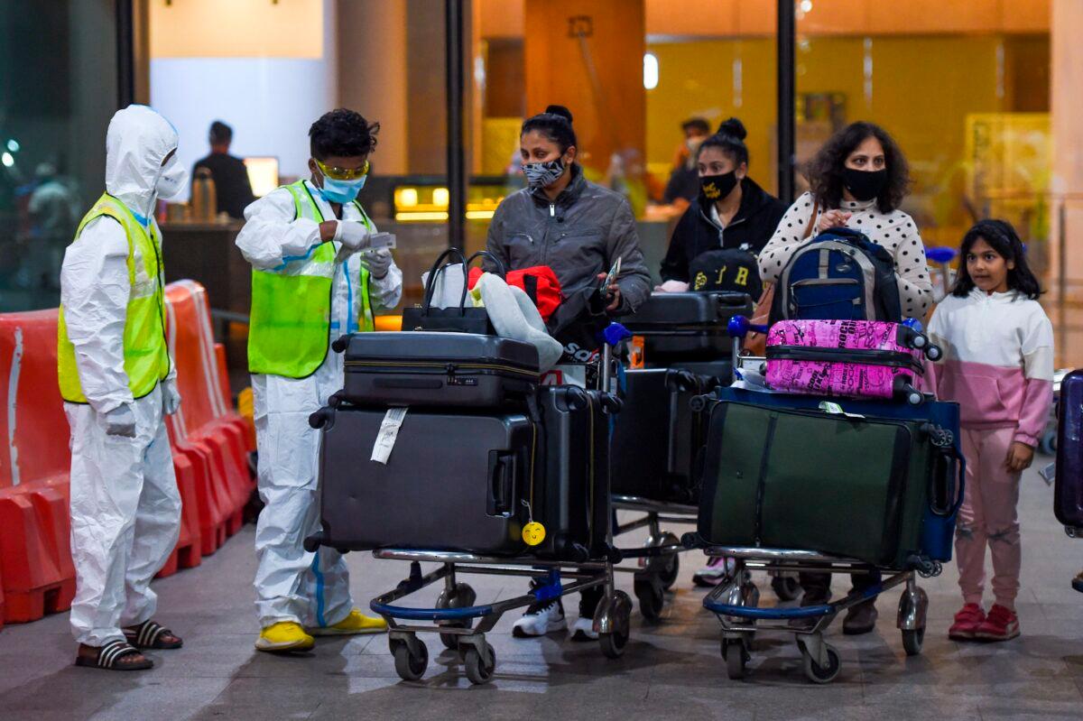 Health workers keep vigil as passengers exit the Chhatrapati Shivaji International Airport upon their arrival from London in Mumbai on Dec. 22, 2020. (Punit Paranjpe/AFP via Getty Images)