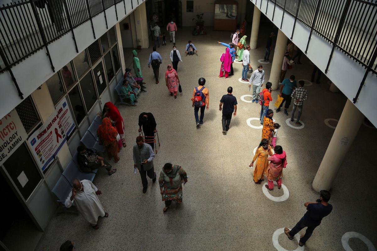 People stand on social distancing markings at a government hospital in Jammu, India, on April 19, 2021. (Channi Anand/AP Photo)