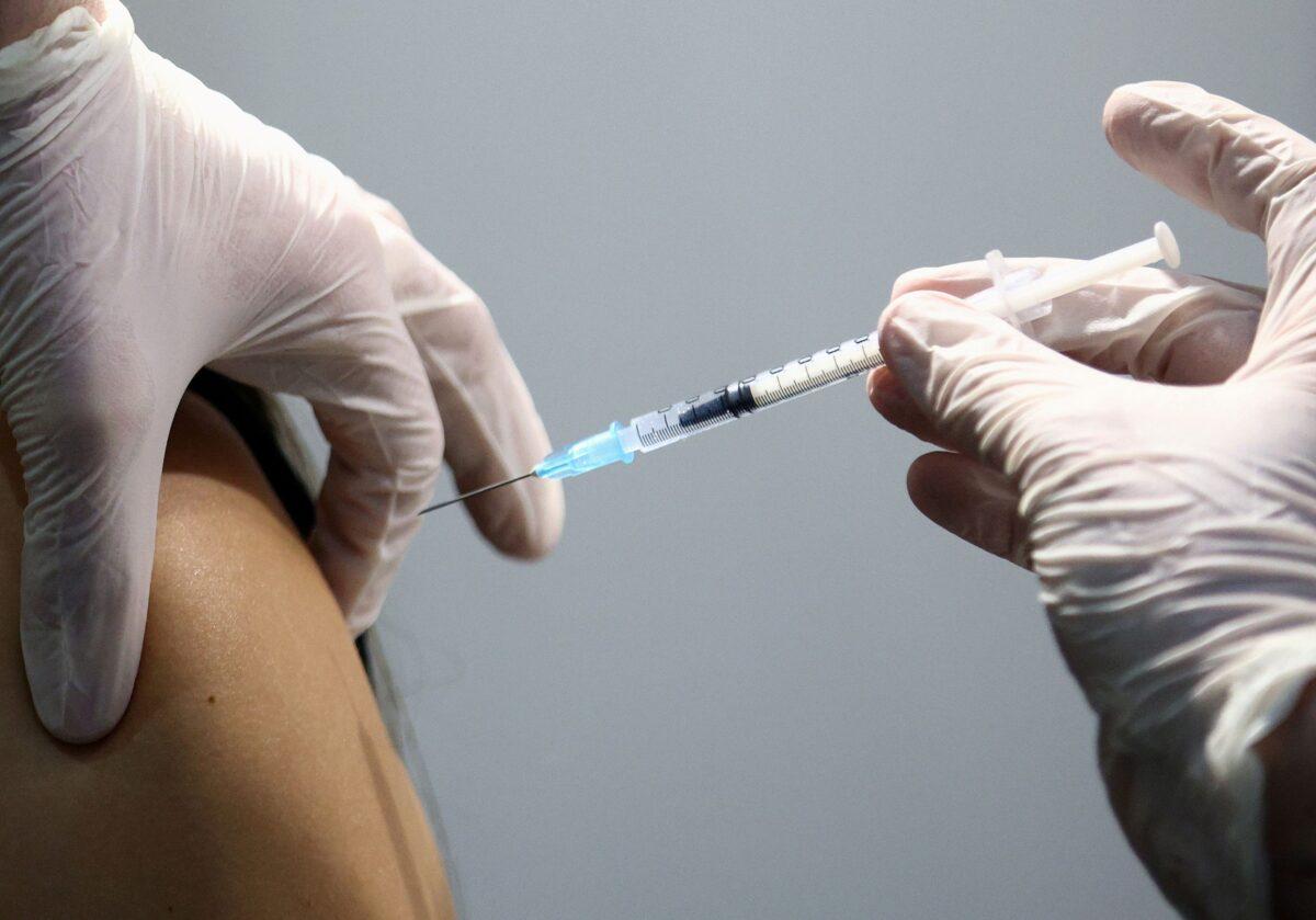 A healthcare worker receives a dose of a Pfizer-BioNTech COVID-19 vaccine at Messe Wien Congress Center, which has been set up as a coronavirus disease vaccination center, in Vienna, Austria, on Feb. 7, 2021. （Lisi Niesner/Reuters)