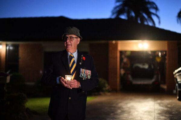 A veteran holds a candle during the Anzac Day dawn service outside his house on ANZAC Day, Apr. 25, 2020, in Sydney, Australia. (Photo by SAEED KHAN/AFP via Getty Images)