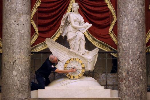 An employee from the Architect of the Capitol adjusts the hands of the Car of History Clock in Statuary Hall at the U.S. Capitol in Washington on Oct. 31, 2019. (Chip Somodevilla/Getty Images)