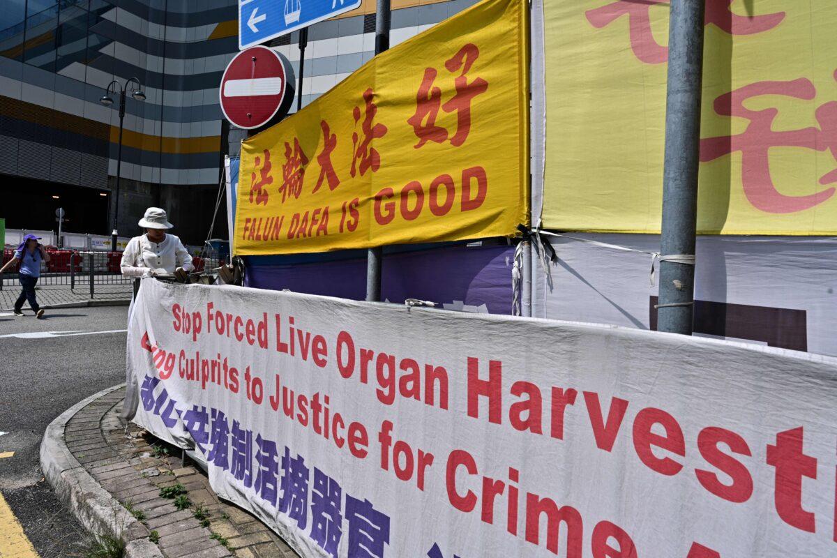 A woman adjusts banners in support of the Falun Gong spiritual movement, a group banned in mainland China, in Tung Chung, an area popular with tourists from the mainland, in Hong Kong on April 25, 2019. (Anthony Wallace/AFP via Getty Images)