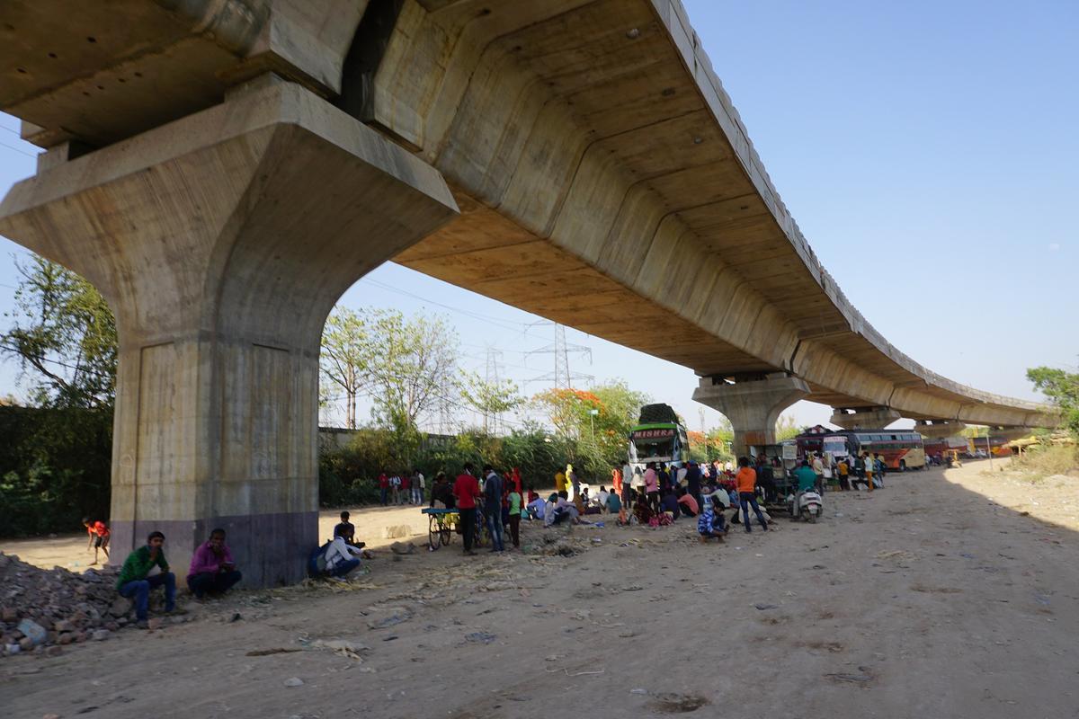 People wait outside private run buses in Sarai Kale Khan on April 21, 2021, to return home after the lockdown was imposed in Delhi. (Venus Upadhayaya/Epoch Times)