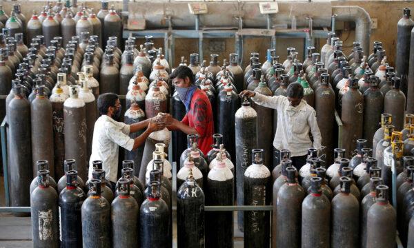 People carry oxygen cylinders after refilling them in a factory amidst the spread of the CCP virus disease (COVID-19) in Ahmedabad, India, on April 25, 2021. (Amit Dave/Reuters)