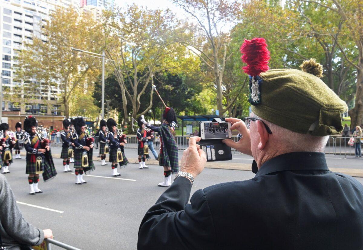 A veteran films a band with his phone as Australian military personnel, past and present, commemorate ANZAC Day during a march through the city centre in Sydney, Australia, on April 25, 2021. (Jaimi Joy/Reuters)
