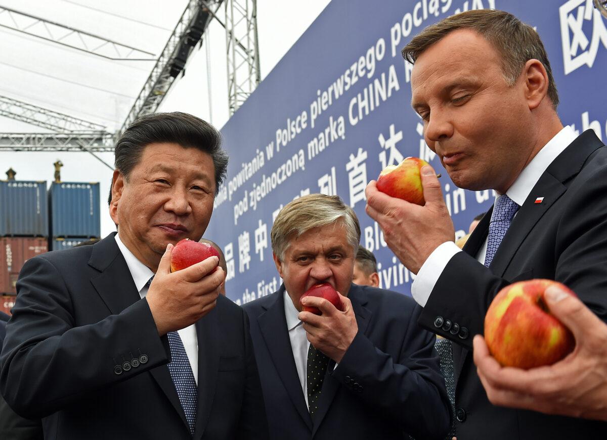 Chinese leader Xi Jinping (L) and Polish President Andrzej Duda (R) eat Polish apples as they greet the arrival of the first China Railway Express train rolling into Warsaw on June 20, 2016. (Janek Skarzynski/AFP via Getty Images)