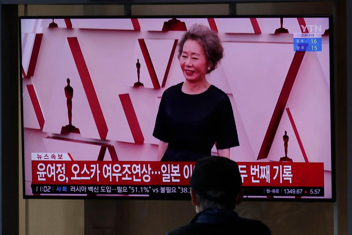A visitor watches a TV screen showing a news program with file footage reporting South Korean actress Yuh-Jung Youn received the Oscar for best supporting actress for her performance in “Minari,” at Seoul Railway Station in Seoul, South Korea, on April 26, 2021. (Lee Jin-man/AP Photo)