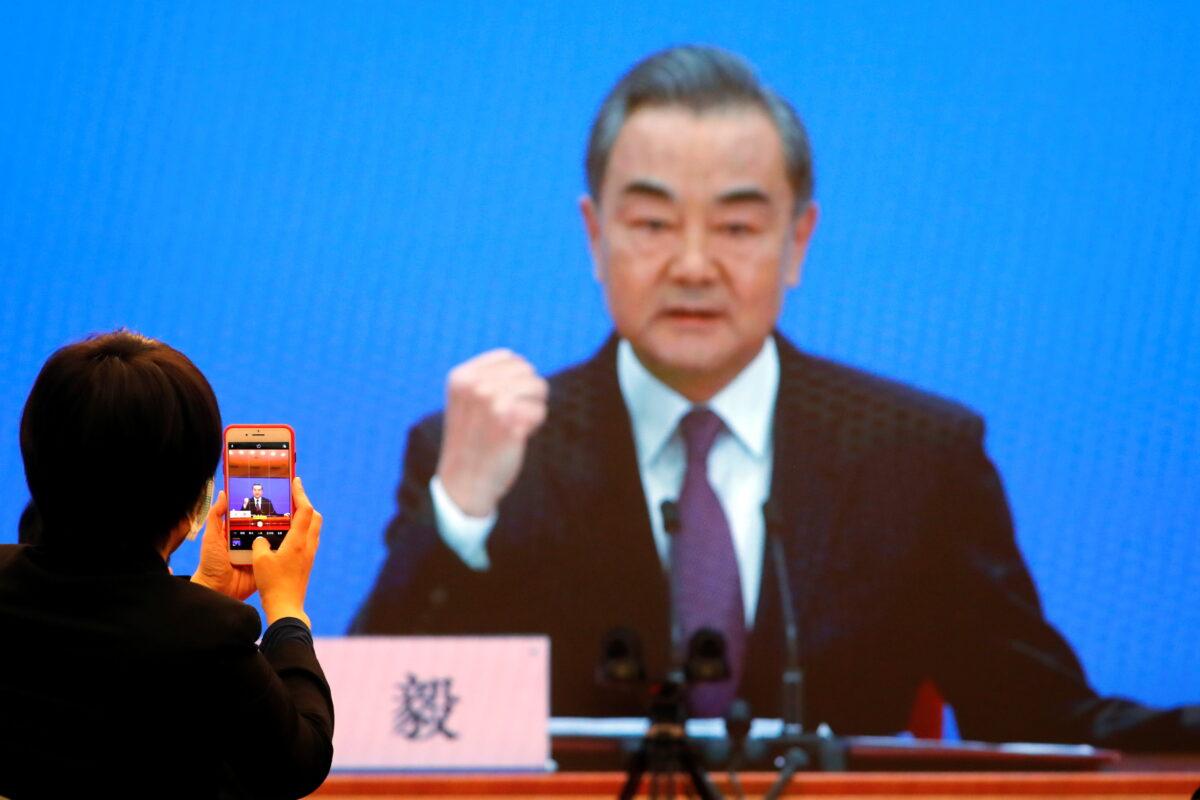 Chinese State Councilor and Foreign Minister Wang Yi is displayed on a screen as he attends via video link a news conference on the sidelines of the National People's Congress (NPC), in Beijing on March 7. (Thomas Peter/Reuters)