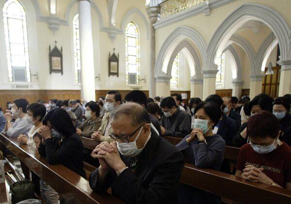 Catholics pray at mass in Hong Kong's Roman Catholic Cathedral in Central district wearing masks to protect against Severe Acute Respiratory Syndrome (SARS) on Good Friday, on April 18, 2003. (Peter Parks/AFP via Getty Images)
