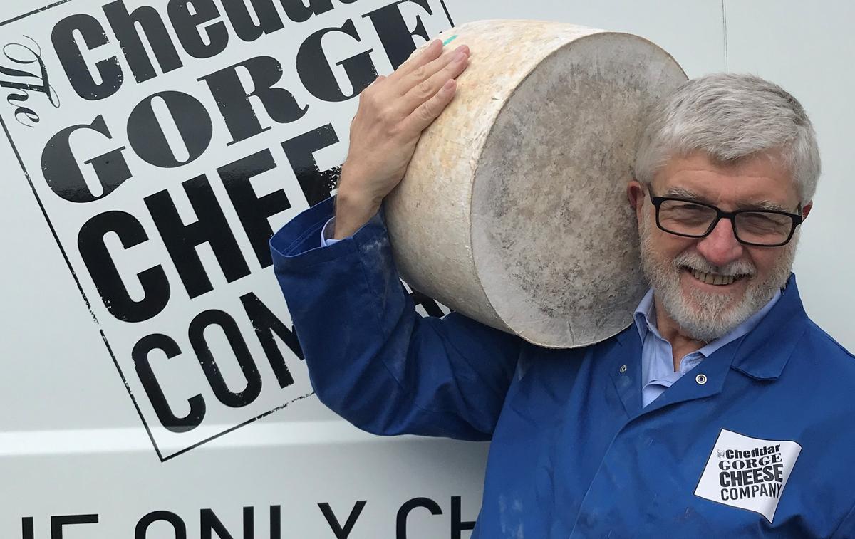 John Spencer carrying a 26-month-old whole Vintage Cheese—26 kilograms (about 57 pounds) in weight. (Courtesy of Cheddar Gorge Cheese Company)
