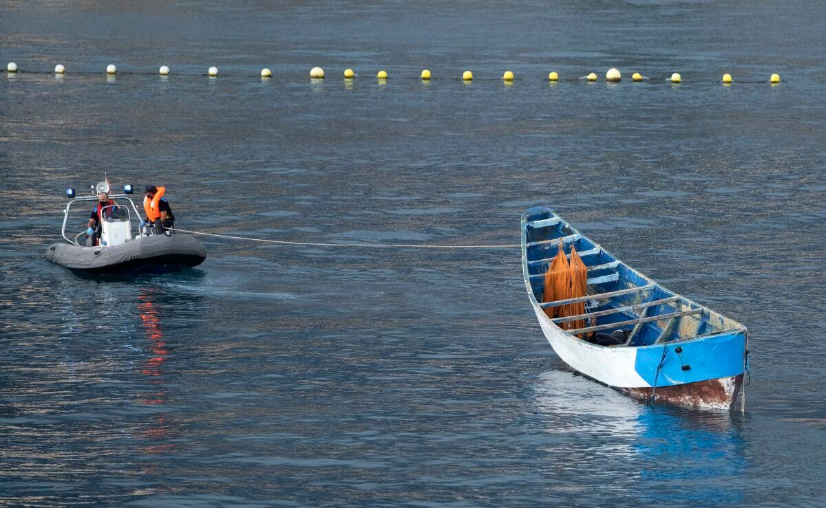 A wooden boat carrying the bodies of dead bodies of migrants is towed by emergency services as they arrive at the port of Los Cristianos in the south of Tenerife, in the Canary Islands, Spain, on April 28, 2021. (Andres Gutierrez/AP Photo)