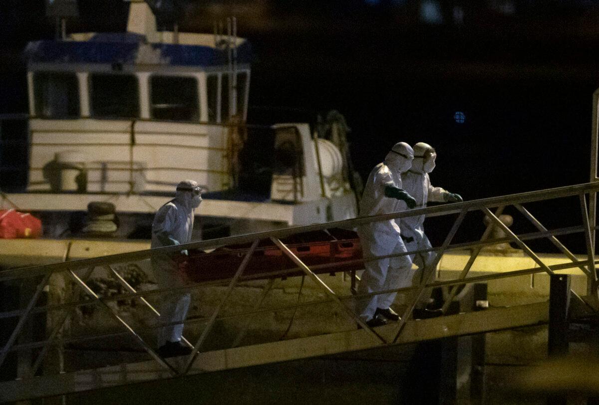 Emergency services carry the dead bodies of migrants after being recovered from a wooden boat at the port of Los Cristianos in the south of Tenerife, in the Canary Islands, Spain, on April 28, 2021. (Andres Gutierrez/AP Photo)