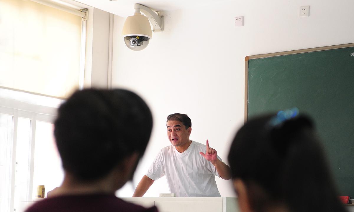 Ilham Tohti, a Uyghur professor of economics, delivers his lecture under a security surveillance camera mounted above the teacher's podium in a classroom in Beijing on June 12, 2010. (Frederic J. Brown/AFP via Getty Images)