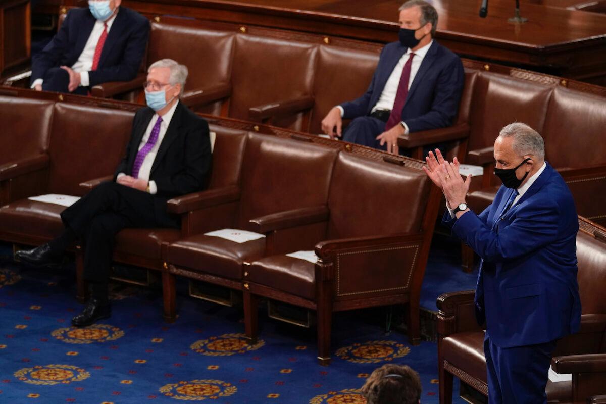 Senate Majority Leader Chuck Schumer (D-N.Y.) stands as Senate Minority Leader Mitch McConnell (R-Ky.) remains seated during a speech by President Joe Biden before a joint session of Congress in the House chamber of the U.S. Capitol in Washington, on April 28, 2021. (Andrew Harnik-Pool/Getty Images)
