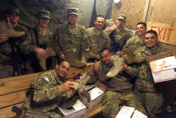 U.S. troops hold up boots received in care packages sent by Helping Soldiers in the Desert. (Courtesy of Si Tenenberg)