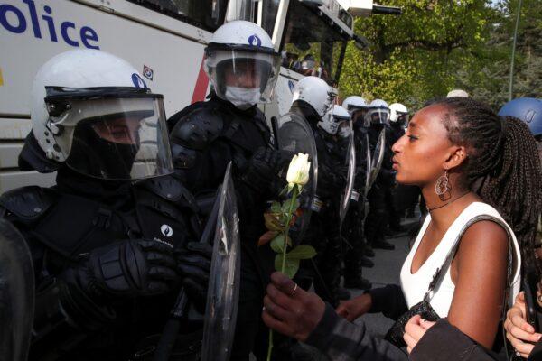A woman hands a flower to a police officer as people gather at the Bois de la Cambre/Ter Kamerenbos park for a party called "La Boum 2" in defiance of Belgium's coronavirus disease (COVID-19) social distancing measures and restrictions, in Brussels, Belgium, on May 1, 2021. (Yves Herman/Reuters)