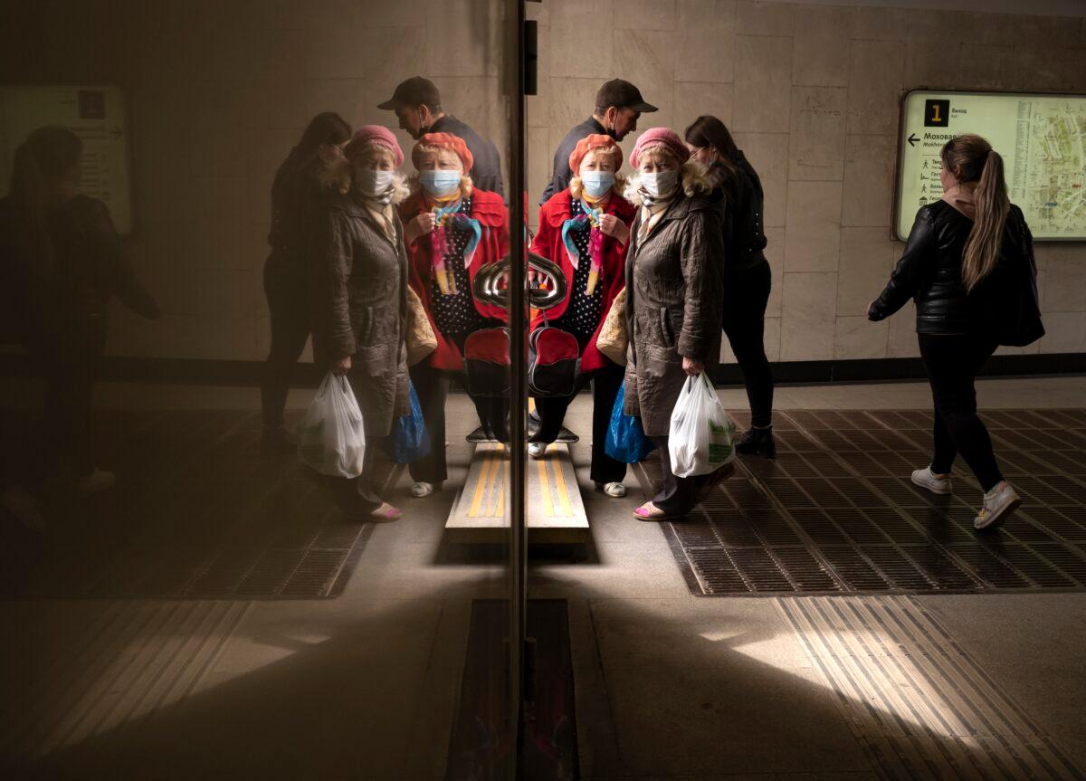 People, some of them wearing face masks to protect against coronavirus, are reflected in a marble wall of an underpass as they walk in Moscow, Russia, on April 19, 2021. (Alexander Zemlianichenko/AP Photo)