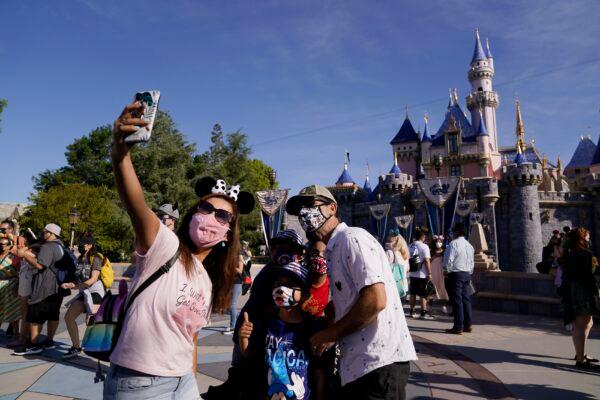 A family takes a photo in front of Sleeping Beauty's Castle at Disneyland in Anaheim, Calif., on April 30, 2021. (Jae Hong/AP Photo)