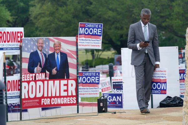 Volunteer Al Green looks at his phone as he takes a break from holding a sign supporting his candidate in a local election outside an early voting location in Mansfield, Texas, on April 27, 2021. (LM Otero/AP Photo)