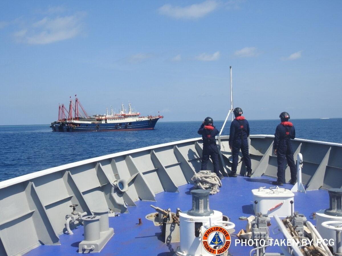 Philippine Coast Guard personnel survey several ships believed to be Chinese militia vessels in Sabina Shoal in the South China Sea, in a handout photo distributed by the Philippine Coast Guard on May 5 and taken according to a source on April 27, 2021. (Philippine Coast Guard/Handout via Reuters)